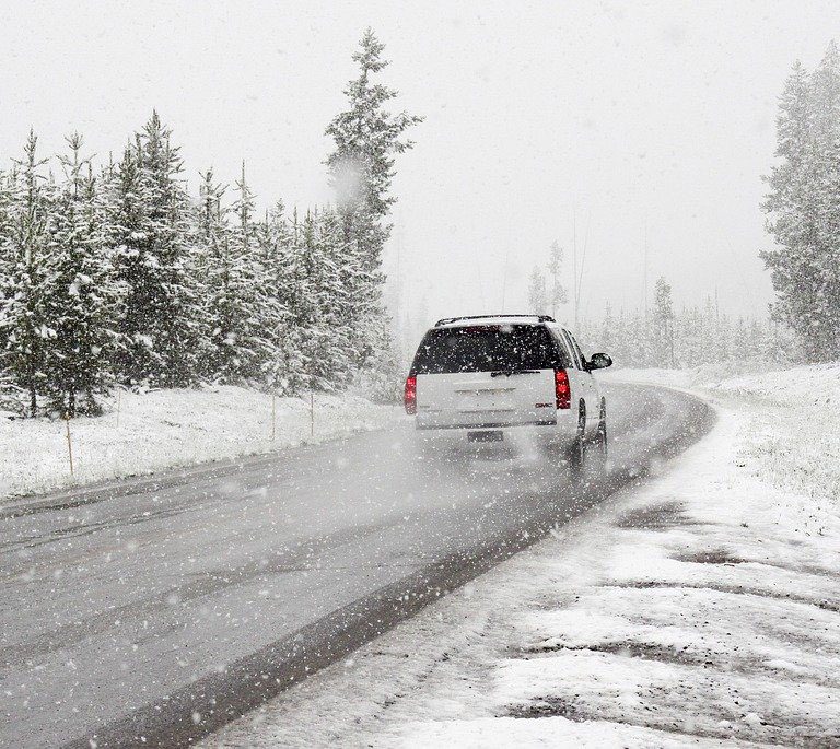 Coche circulando por una carretera nevada en invierno