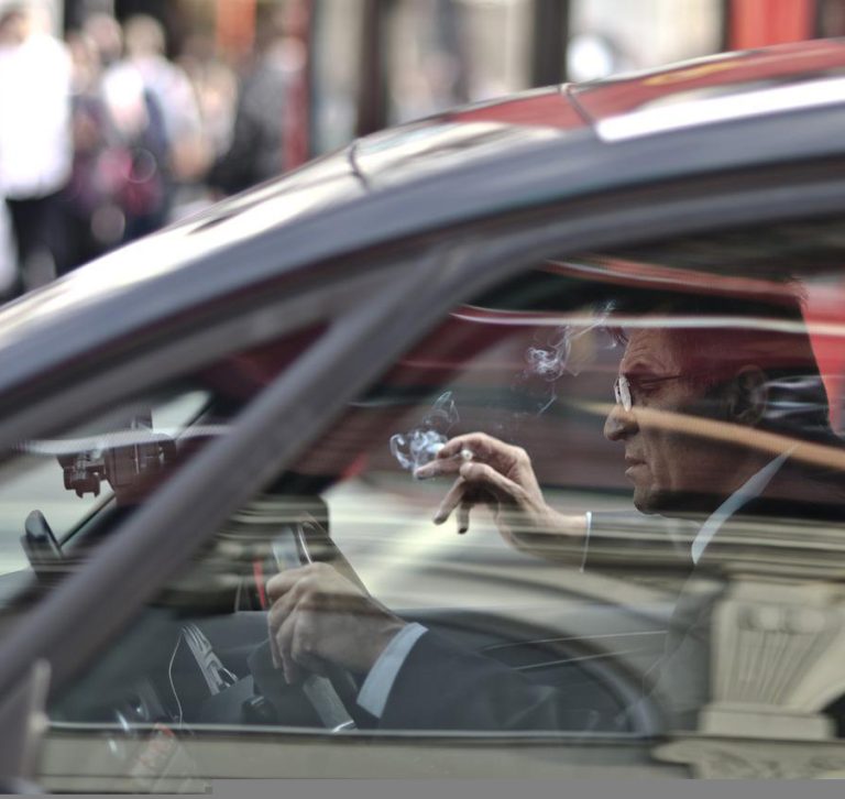 Conductor fumando mientras conduce un coche