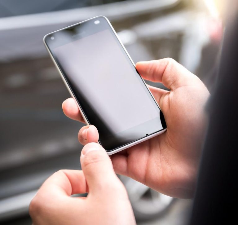 Conductor con el teléfono móvil en la mano fuera del coche